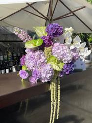 Purple and white flowers with hanging stems above a bar