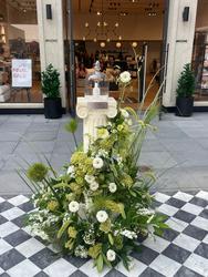 Low white and green floral arrangement on a paved area